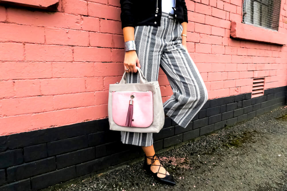 Unknown fashionable woman with striped slacks and statement bag