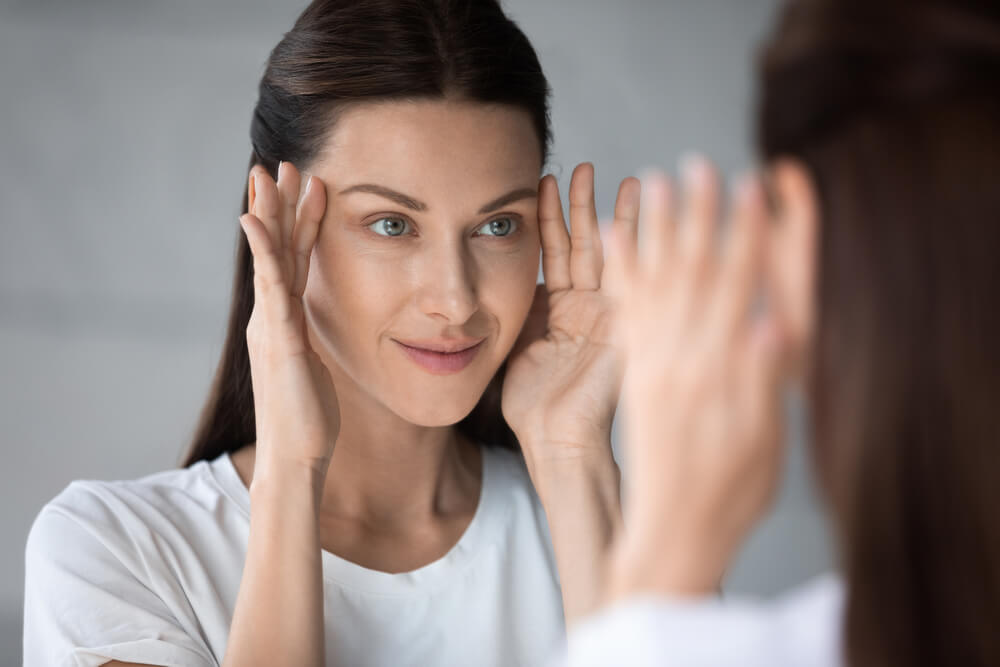 Woman looking at skin in mirror