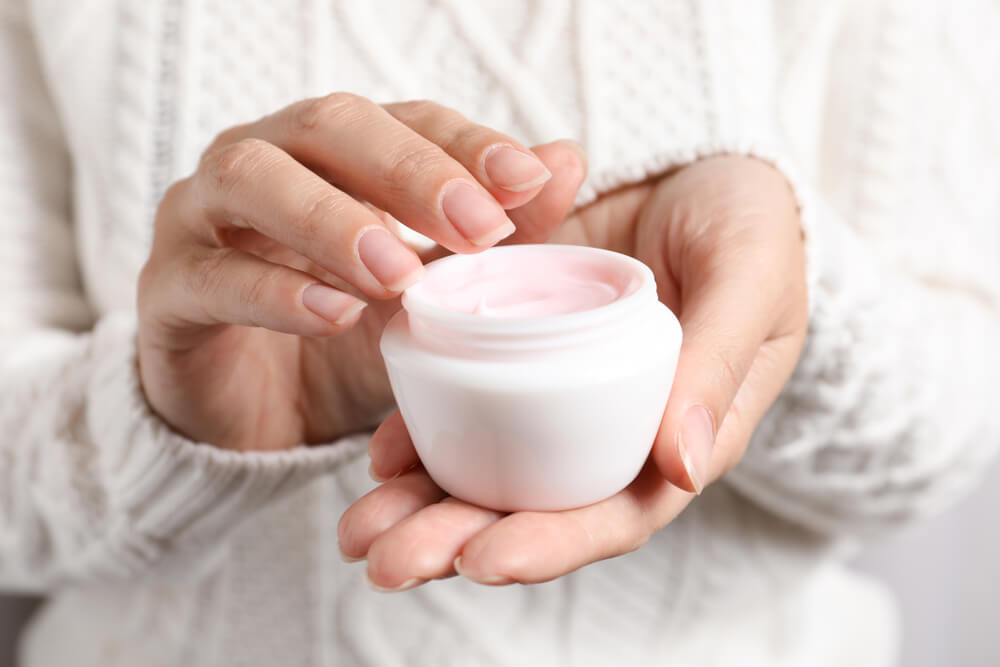 Woman with hand in face cream jar