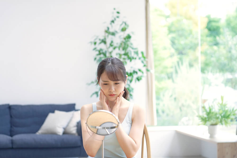 Woman looking at skin in mirror