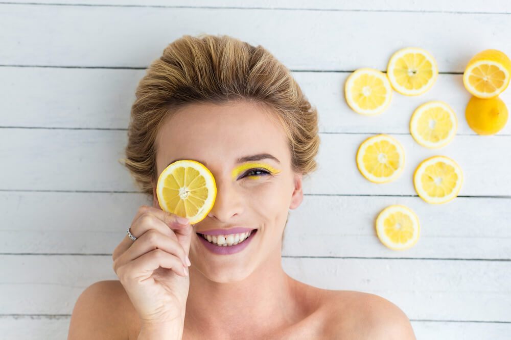 Smiling young woman with a slice of lemon
