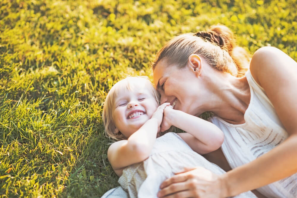 Happy mother playing with her child on the grass