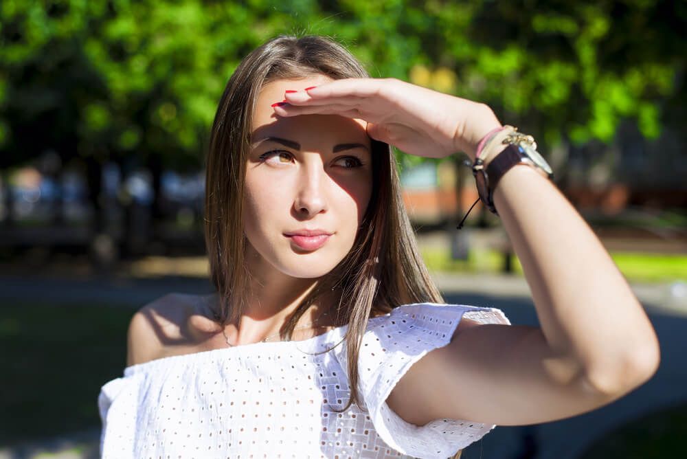 Young woman shielding her face from the sun