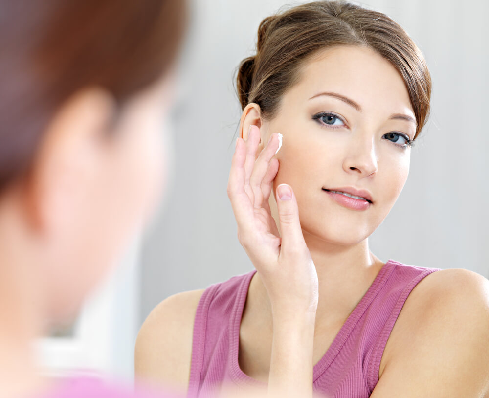 woman applying cream to face