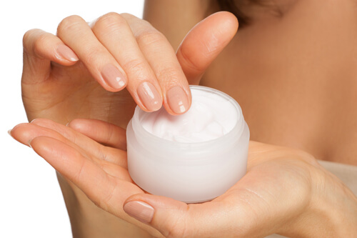 Dipping fingers into a jar of moisturizer