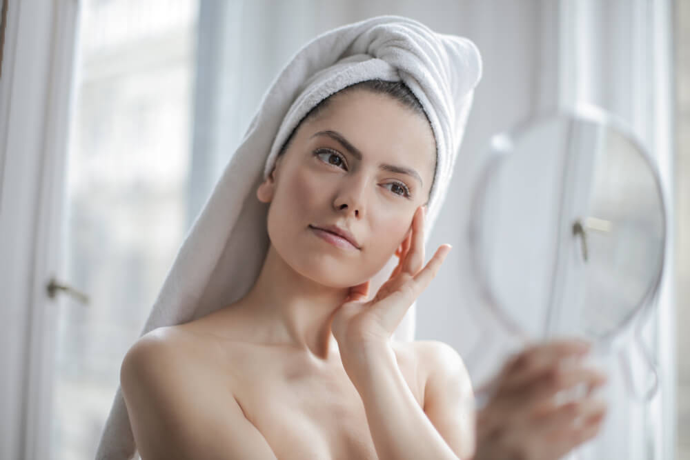 Woman looking at skin in mirror