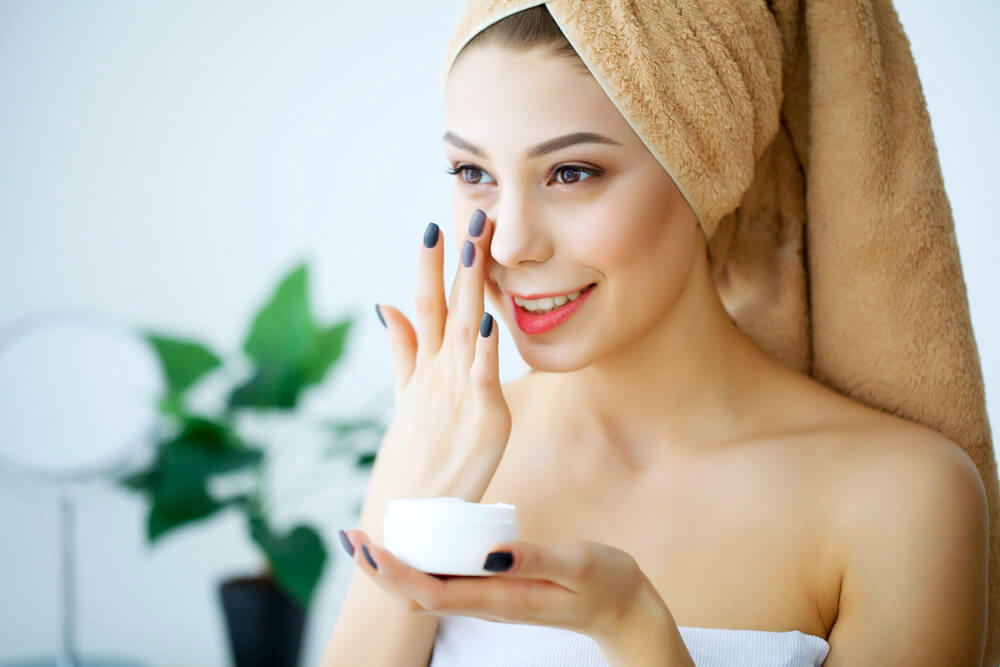 Woman applying moisturizer to face