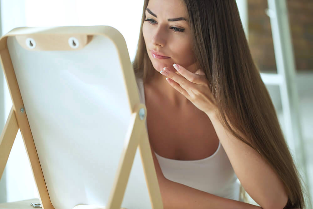 Young woman checking skin in the mirror