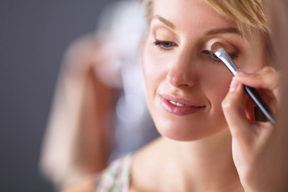 Makeup artist's hand applying eyeshadow to woman's eyes