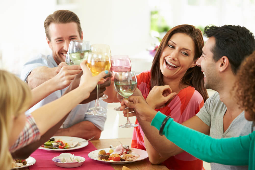 Friends clinking wine glasses over lunch table