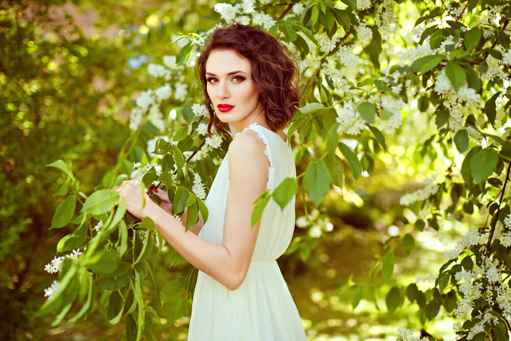 Beautiful young woman in white dress in the garden