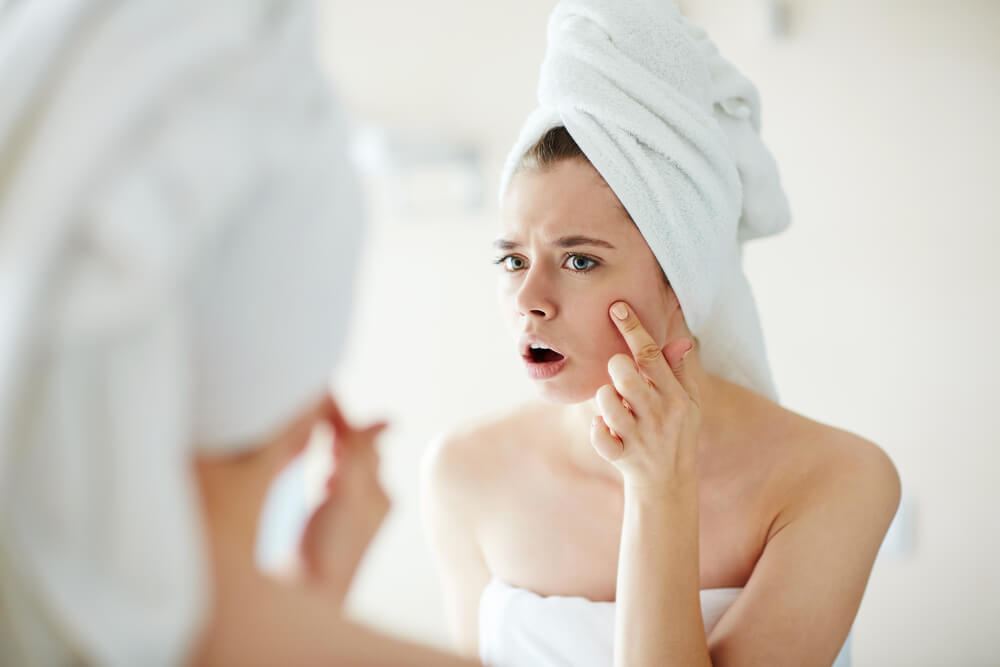 Woman frowning upon discovering a pimple on her face