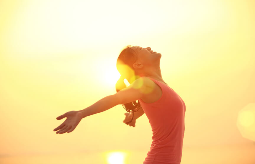 Happy woman with arms outstretched against the sun