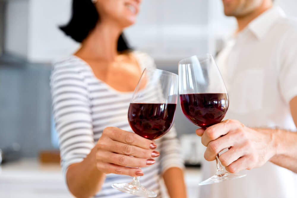 Unknown couple clinking wine glasses together