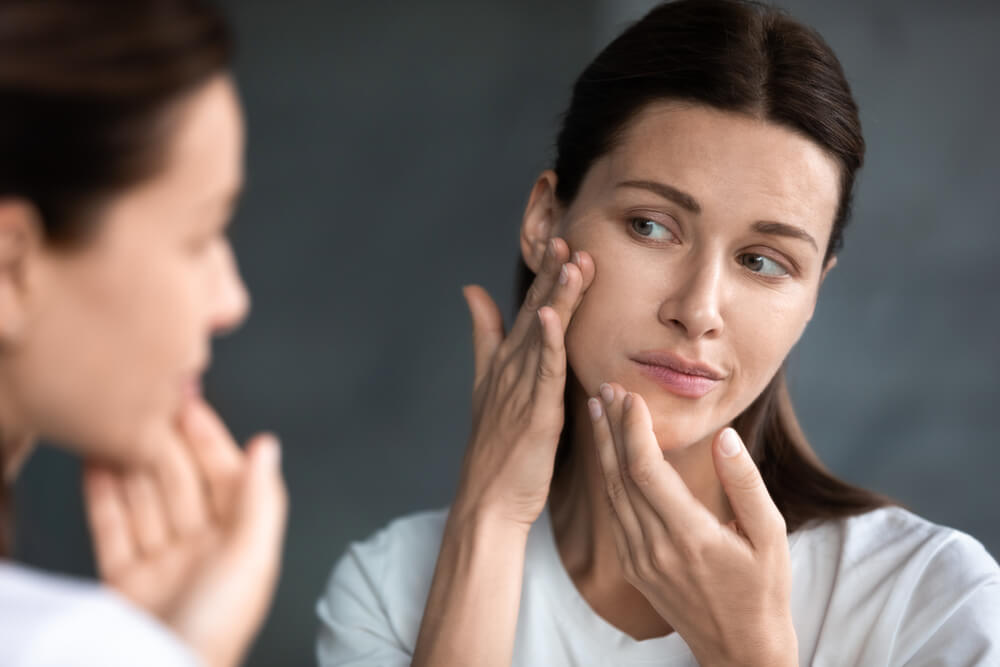 Woman looking at skin in mirror