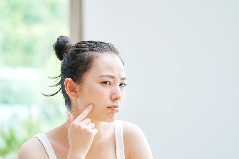 Woman looking at skin in mirror