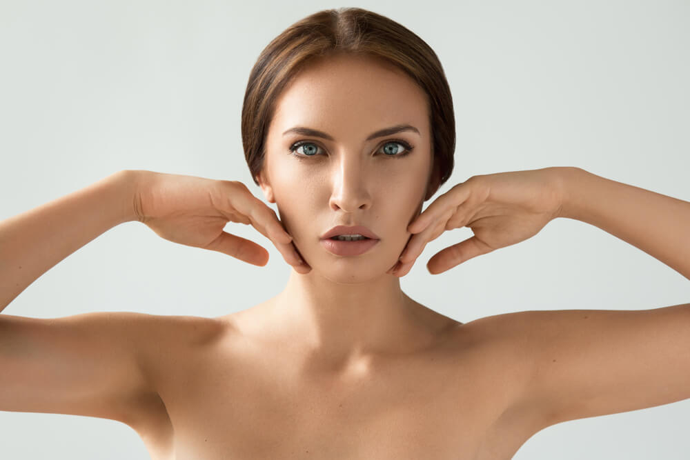 Young fierce-looking woman touching both cheeks
