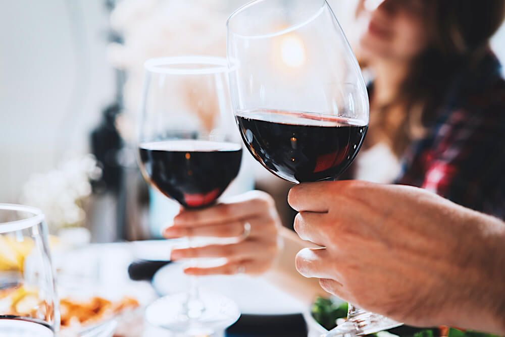 Clinking two wine glasses together over dinner table