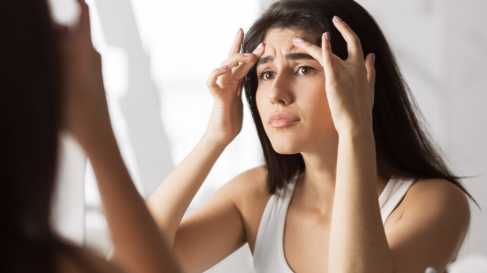 Woman looking at skin in mirror