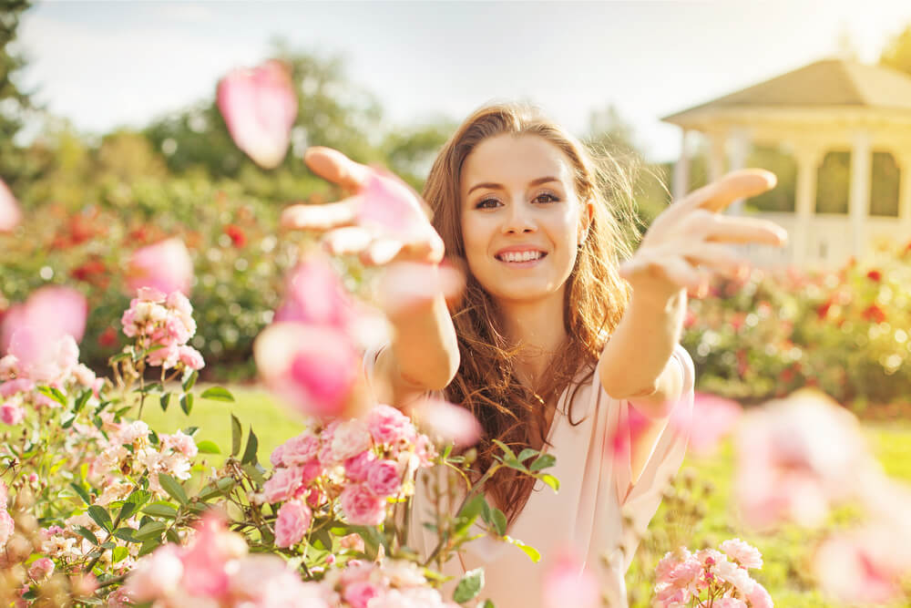 Young woman sprinkling flower petals during spring
