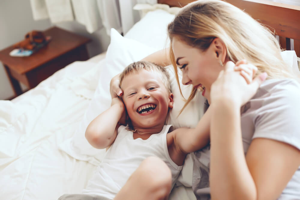 Laughing mother with her young son on the bed