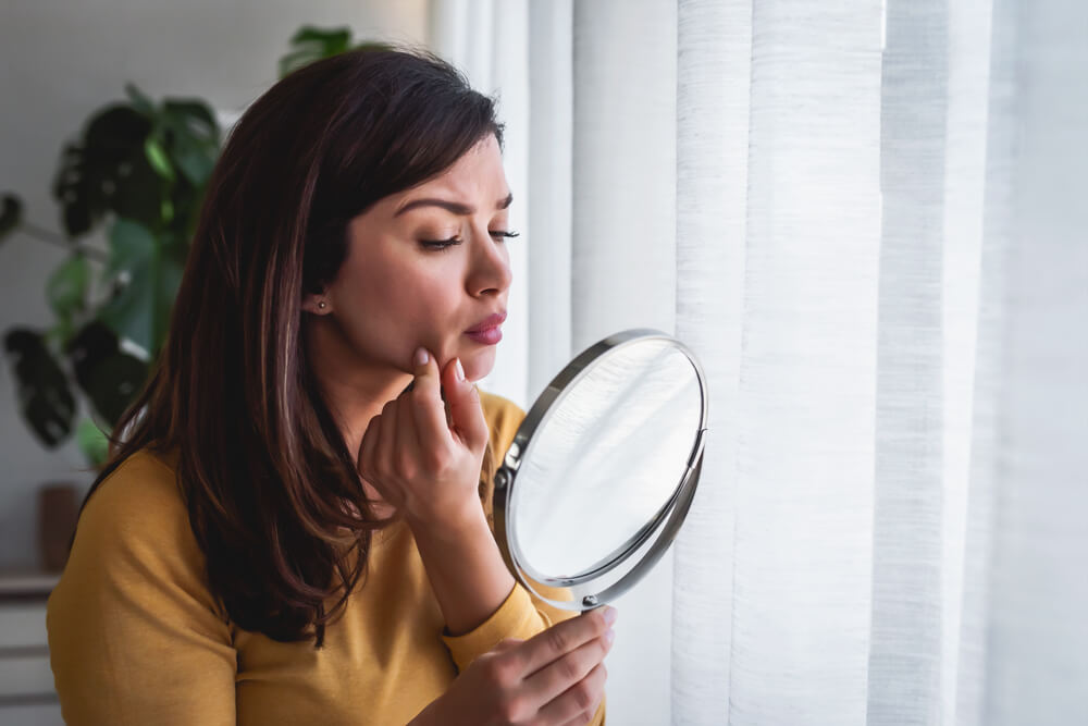 Woman looking at skin in mirror