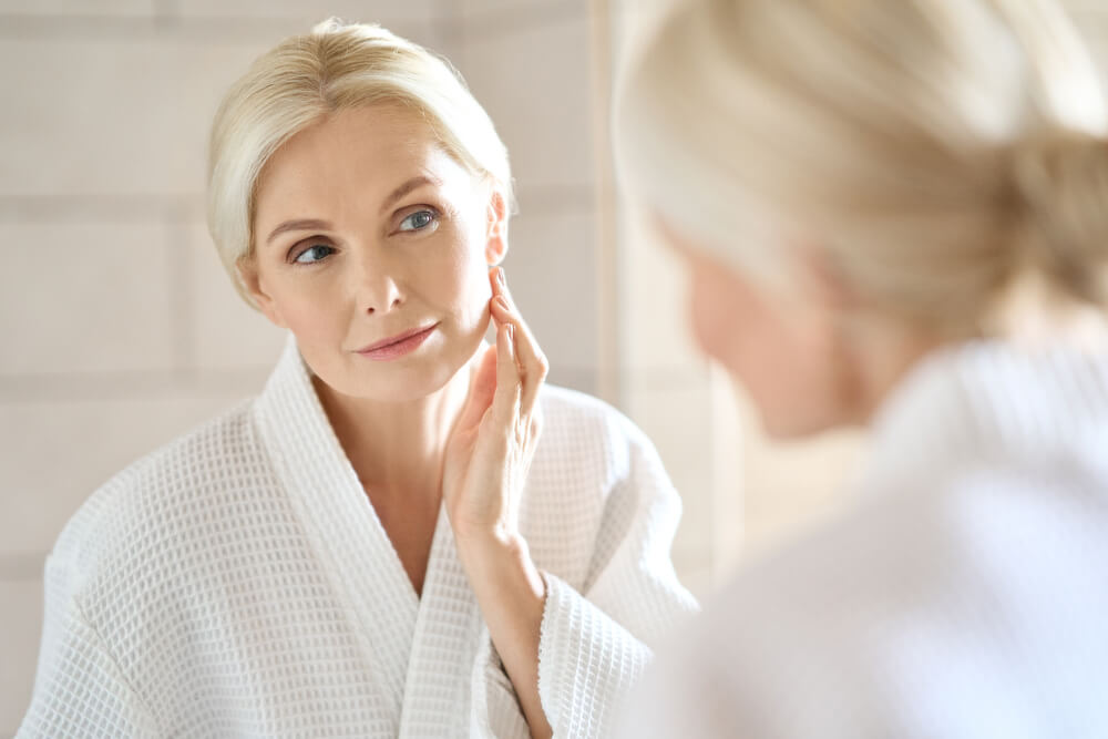 Woman looking at skin in mirror