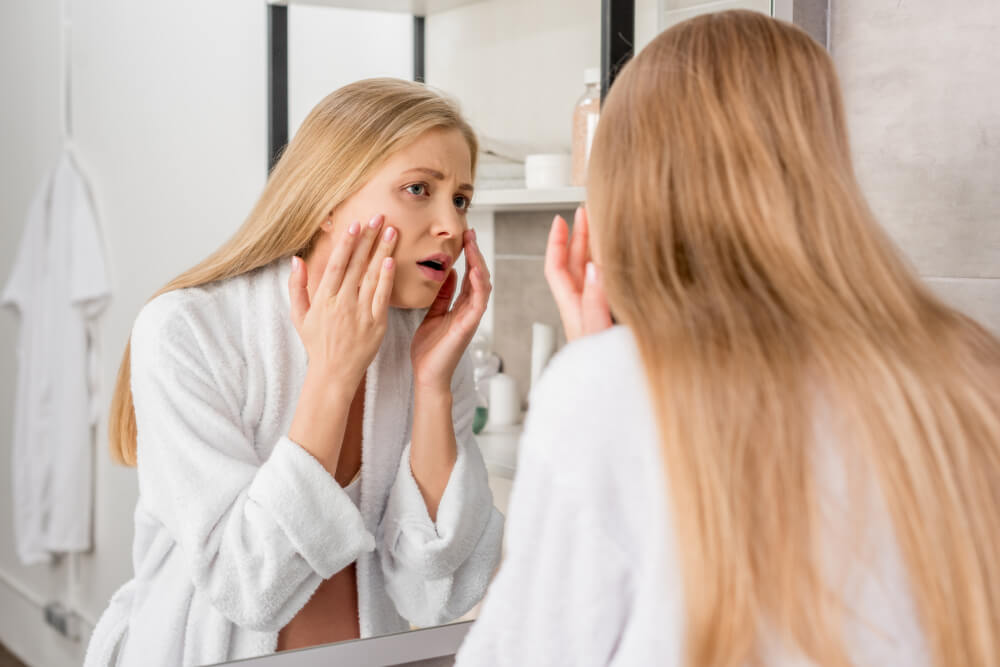 Woman looking at skin in mirror