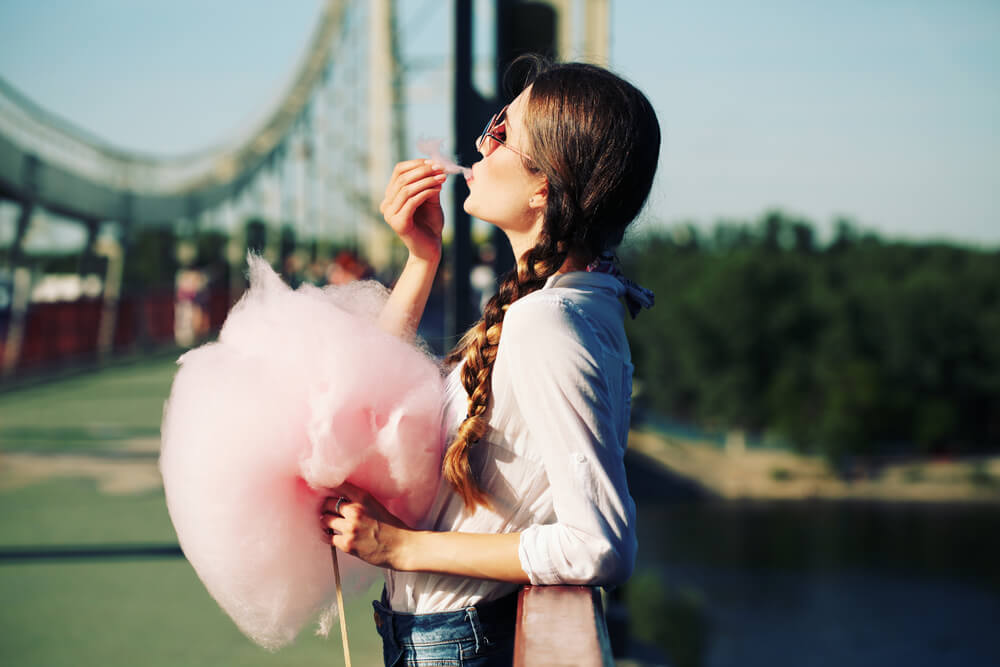 Young woman eating cotton candy outdoors