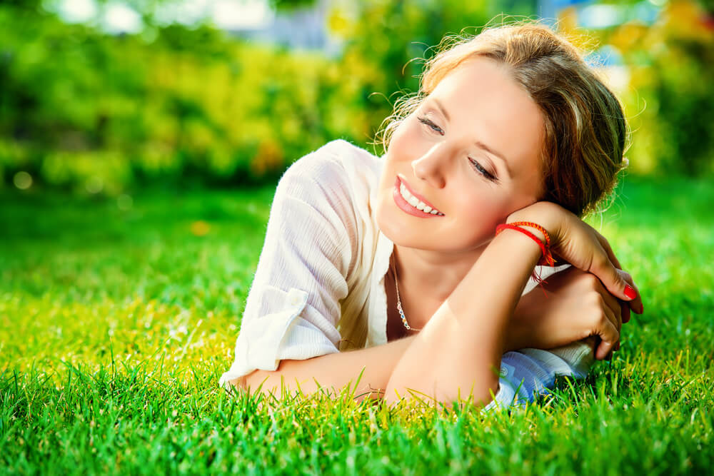 Happy and smiling woman lying on grass