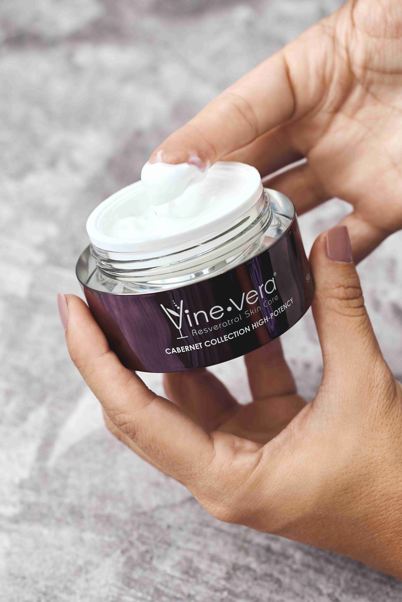 Hand holding the Vine Vera Resveratrol Cabernet Replenishing Moisture Cream SPF 30