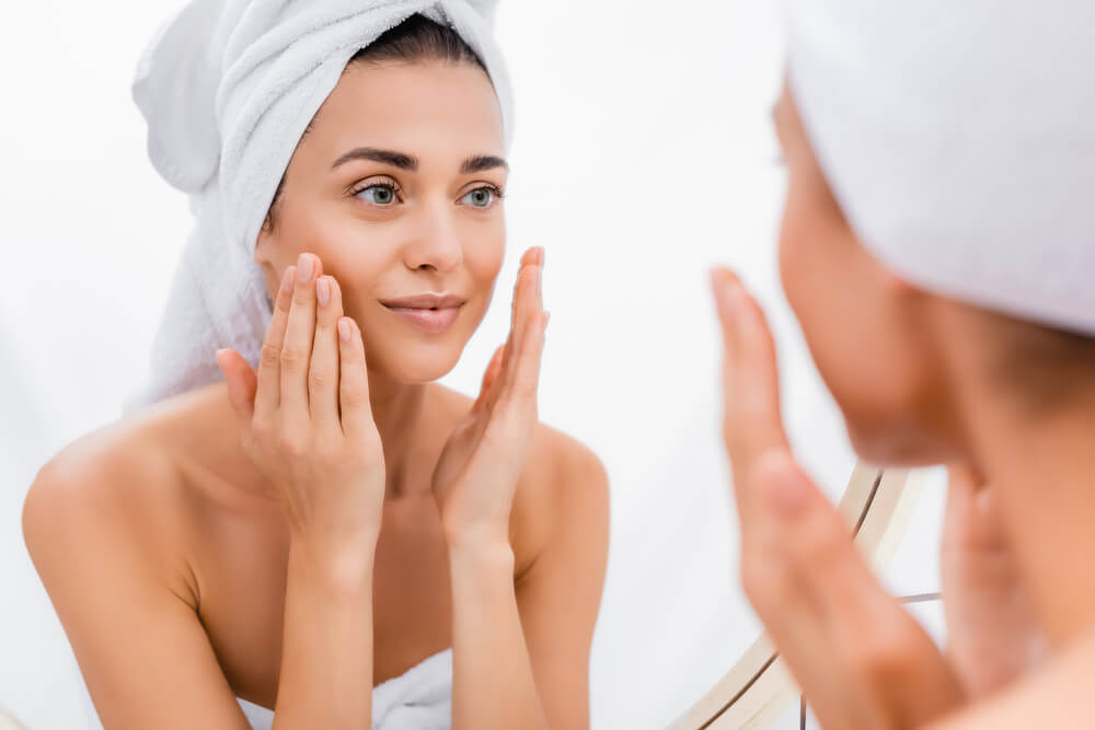 Woman looking at skin in mirror