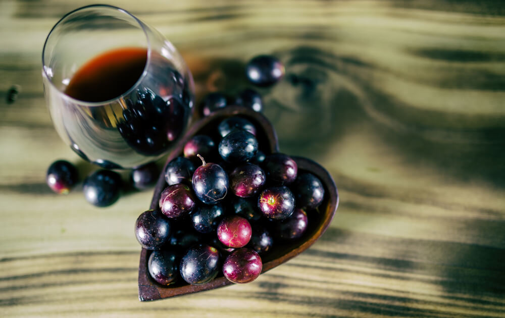 Glass of wine with a heart-shaped bowl of red grapes