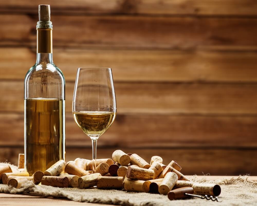 A bottle and glass of white wine on rustic setting