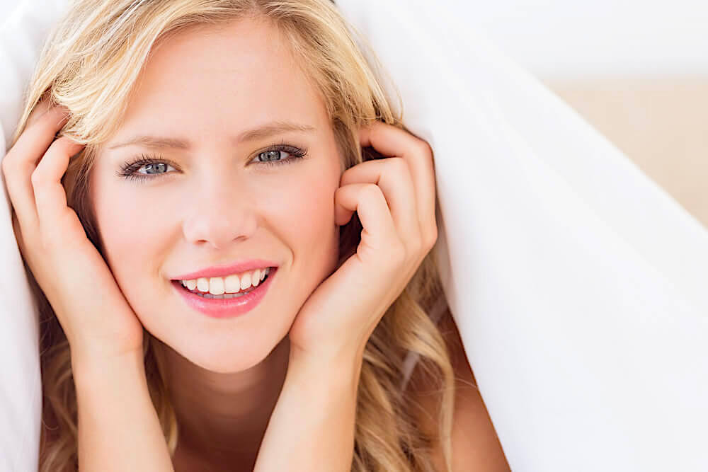 Pretty young woman smiling and touching her face