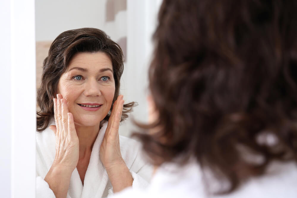 Mature woman checking skin in the bathroom mirror