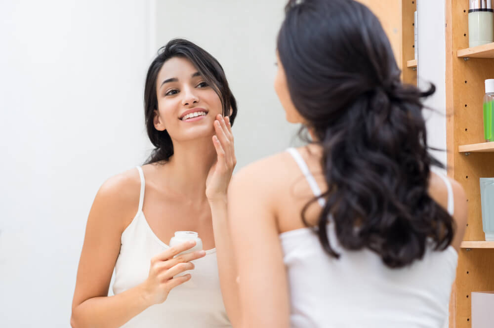 Woman applying moisturiser to skin