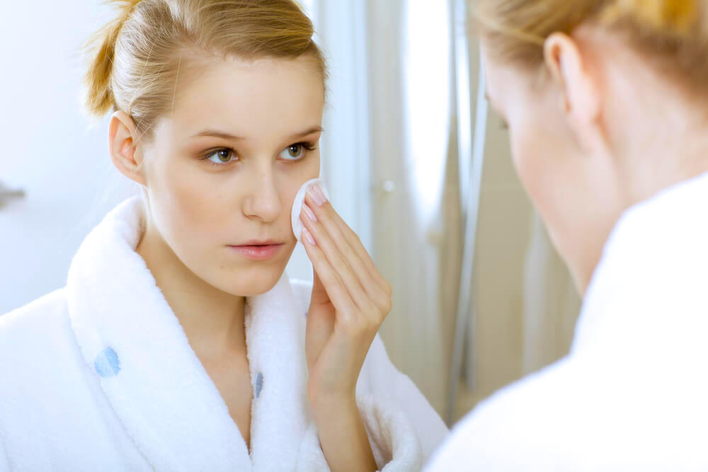 Woman applying skincare using a cotton pad