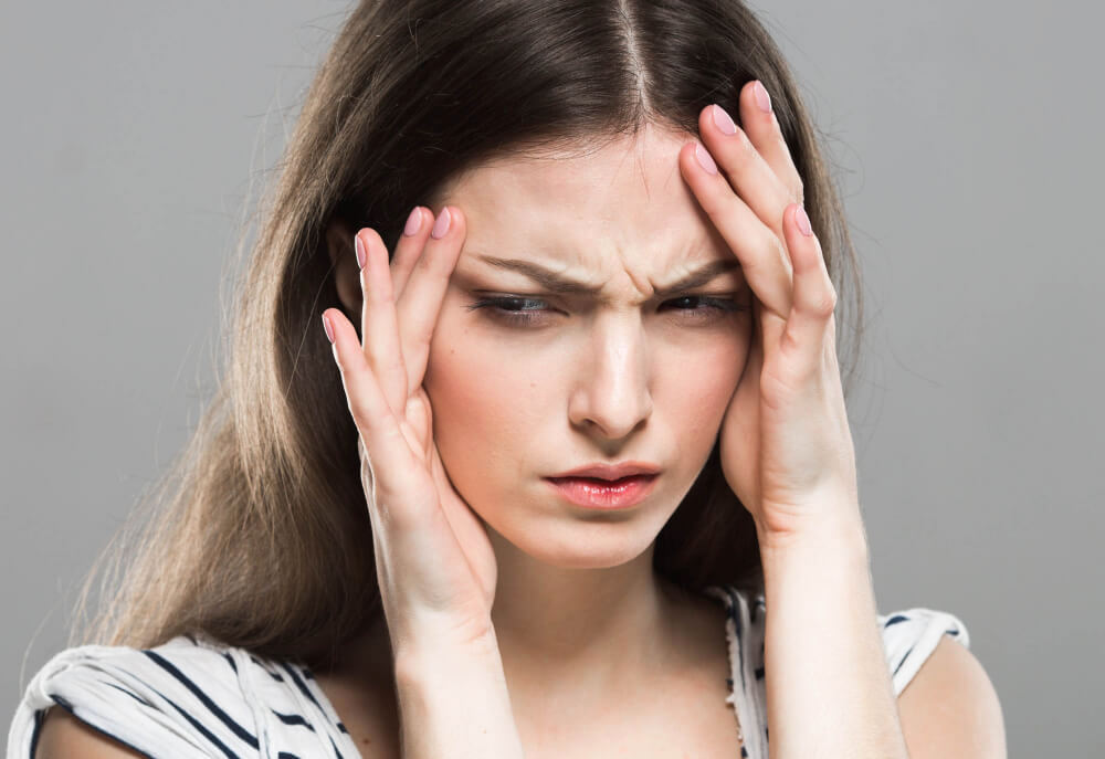 Stressed woman clutching her forehead and face