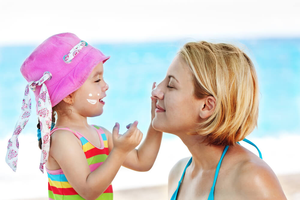 Little girl applying sunscreen on her mom's face