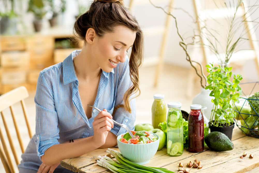 Young woman eating salad in the kitchen