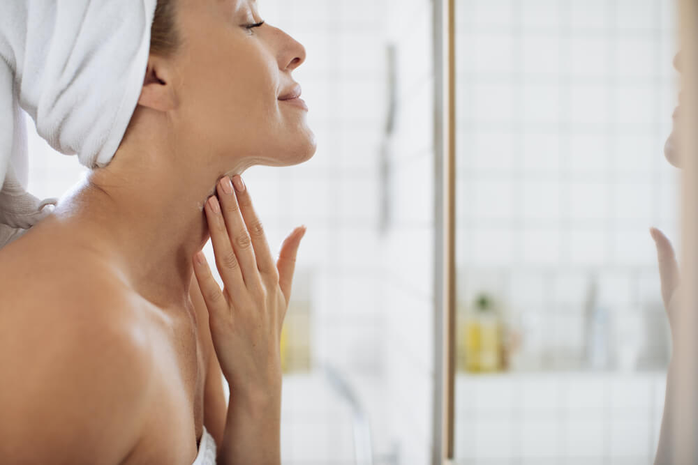 Mujer tocando el cuello delante del espejo