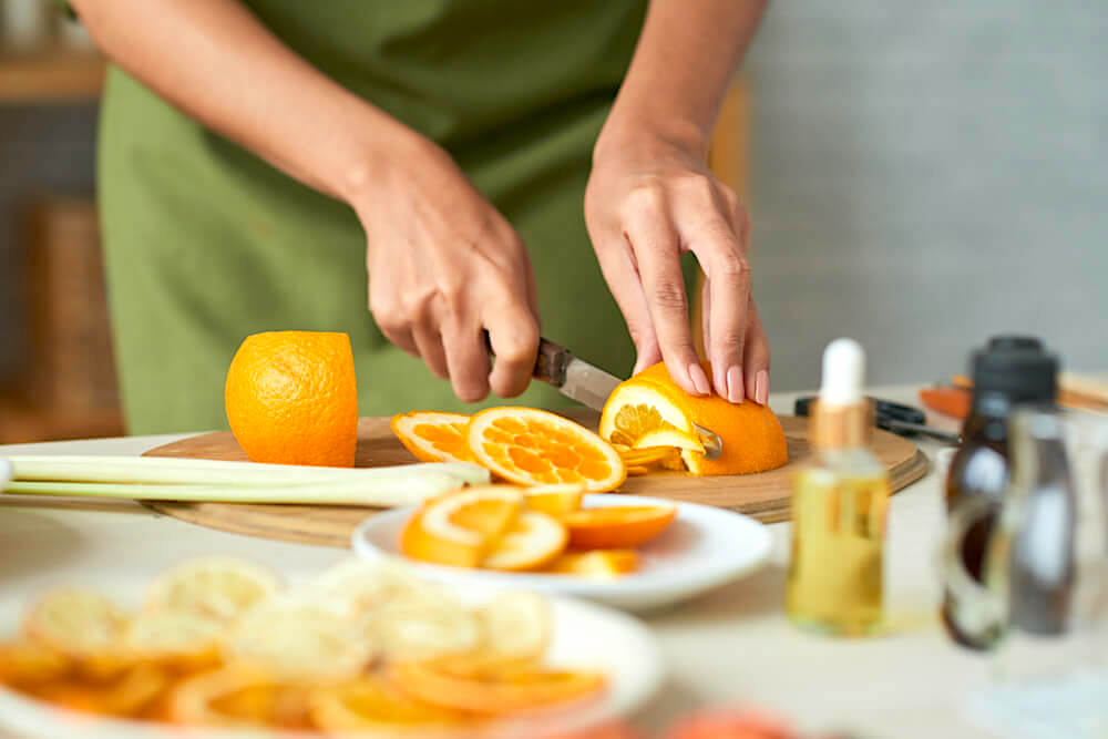 Unknown woman slicing up an orange for skincare purposes