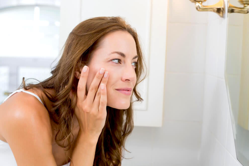 Woman checking her skin in the mirror