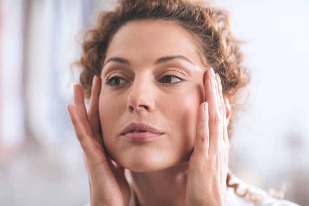 Woman touching her temples and looking into the mirror