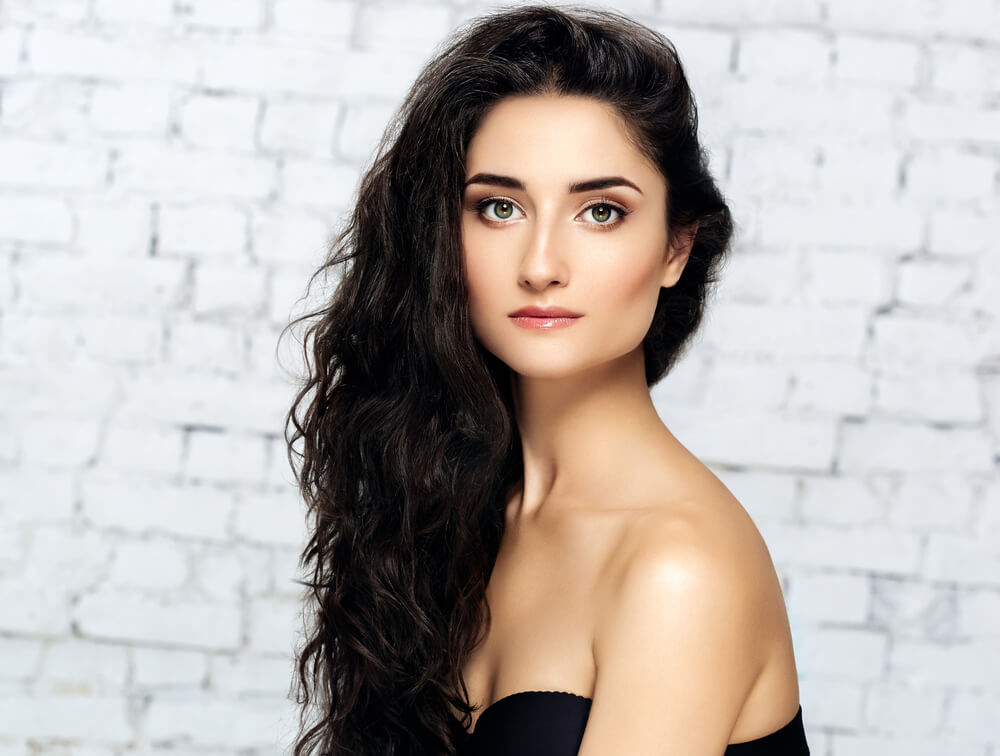 Beautiful dark-haired woman in front of white-bricked wall