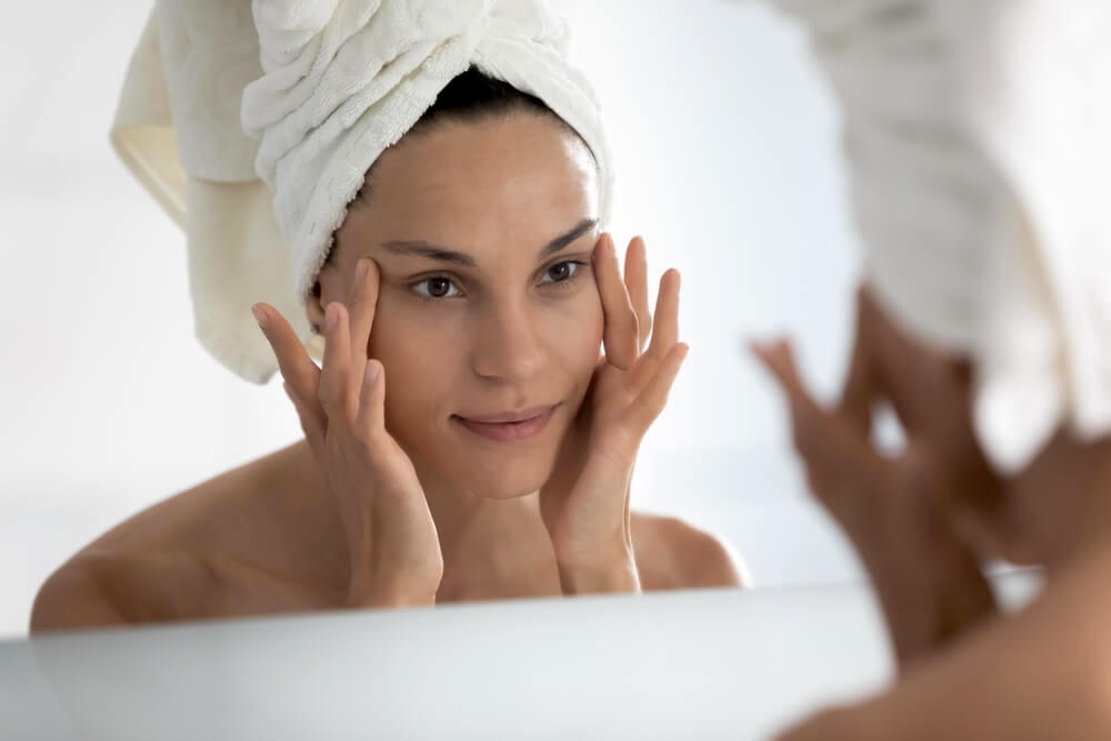 Woman looking at skin in mirror