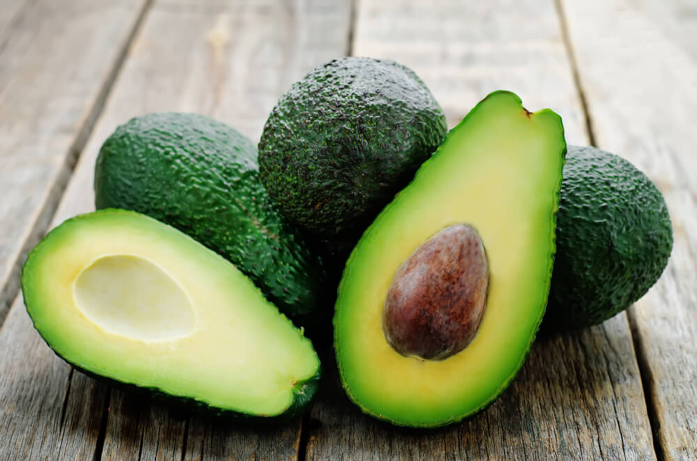 Halved and whole avocados on table
