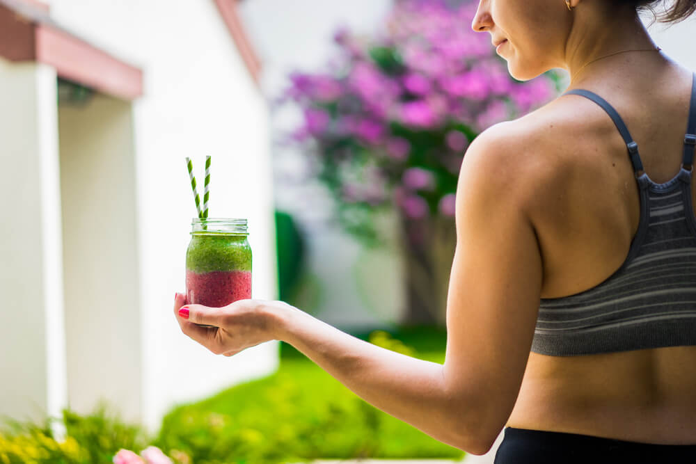 Healthy and fit woman holding a colourful smoothie outdoors